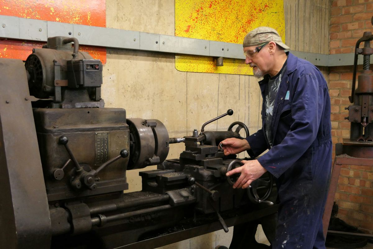 Een vakman aan een draaibank in een werkplaats